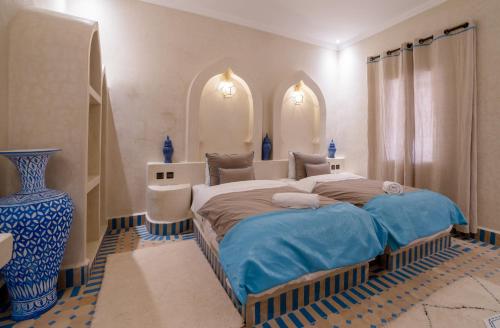 a bedroom with a large bed and a blue vase at Riad Chebbi in Merzouga
