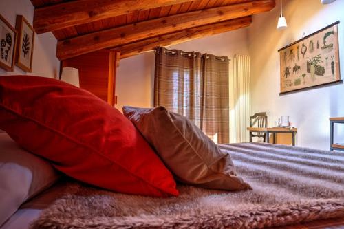 a bedroom with red and brown pillows on a bed at Maison Perriere - Chambres d'hôtes & Jacuzzi in Saint Vincent