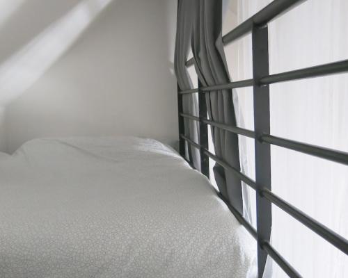 un lit blanc dans une chambre avec une fenêtre dans l'établissement Studio Bastille Lappe CityCosy, à Paris