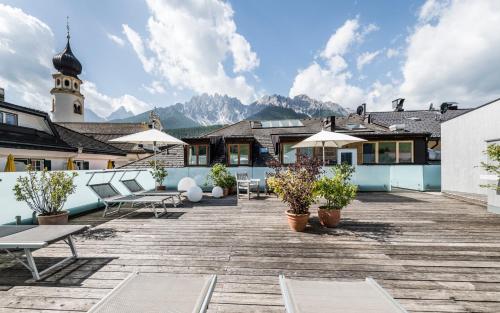 a patio with benches and umbrellas on a building at Boutique & Gourmet Hotel Orso Grigio in San Candido