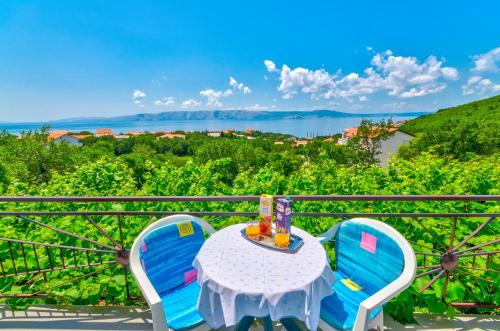 a table and chairs on a balcony with a view of the water at Apartmani Katica in Povile