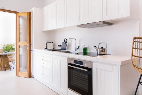 a kitchen with white cabinets and a black dishwasher at Lindian Ethos in Líndos