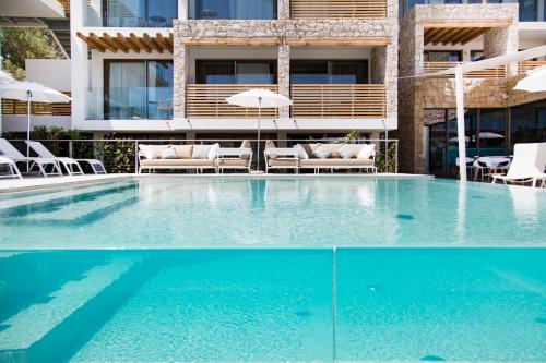 a pool with chairs and umbrellas next to a building at Sandalia Boutique Hotel - Adults Only in Cannigione