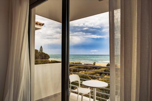 a room with a view of the ocean from a balcony at Atlantis Gardens in Mazotos