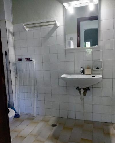 a white tiled bathroom with a sink and a mirror at Alcyon days in Agios Georgios