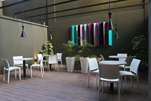 a restaurant with white tables and chairs and plants at The Point Casa Edificio Boutique in San Miguel de Tucumán