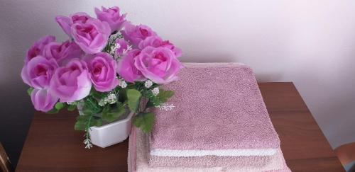 wazon różowych kwiatów na stole w obiekcie Guesthouse Loncar w mieście Jeziora Plitwickie