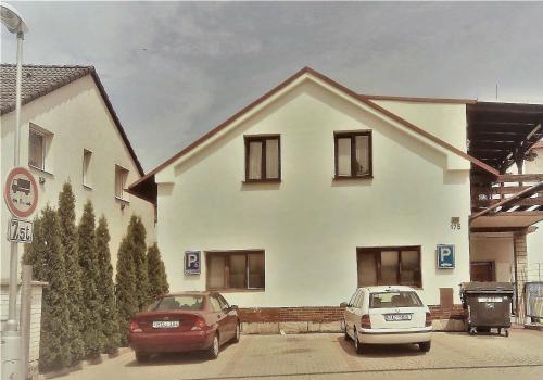 zwei Autos, die vor einem weißen Haus geparkt sind in der Unterkunft Mitrans in Hradec Králové
