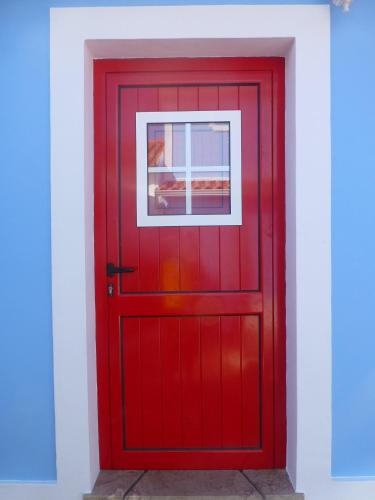 a red door with a window on a white wall at Monte da Cascalheirinha in Santo André