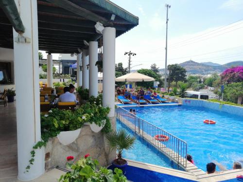 a pool at a resort with people sitting in chairs at Eden Hotel in Bodrum City