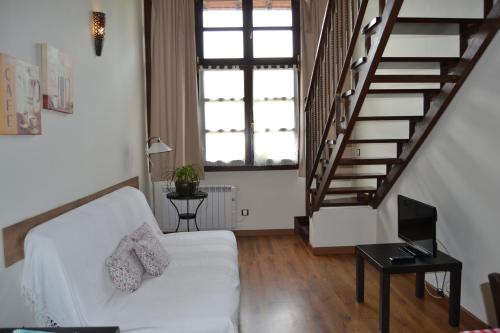 a living room with a white couch and stairs at Apartamentos Rurales La Cirigüeña in Oles