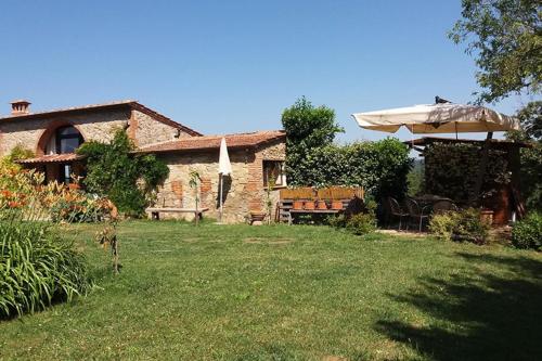 a house with an umbrella and a grass yard at Podere Casalbosco - Idromassaggio e panorama in Rapolano Terme