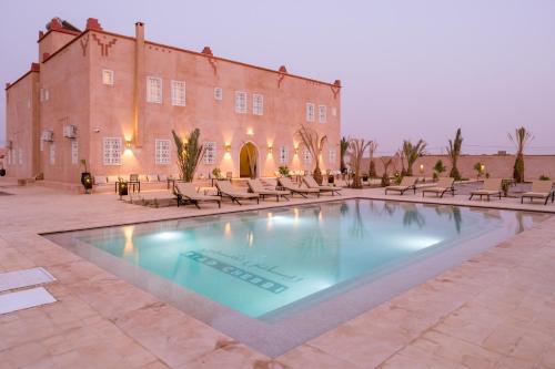 a large swimming pool in front of a building at Riad Chebbi in Merzouga