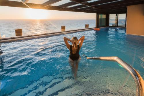 a woman is standing in a swimming pool at Bellevue On The Beach Suites in Rhodes Town