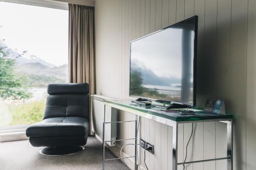 a room with a desk with a television and a chair at Hotel Lago Grey in Torres del Paine