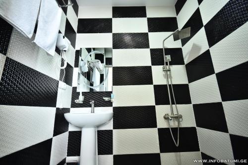 a bathroom with a black and white checkered wall at Hotel Royal Georgia in Batumi