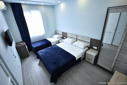 a hotel room with two beds and a mirror at Hotel Royal Georgia in Batumi