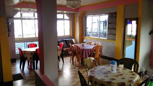 una sala da pranzo con tavoli, sedie e finestre di Vamoose Kanchan Kanya a Sukhia Pokhari
