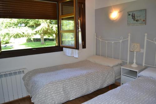 a bedroom with two beds and a window at Apartamentos Rurales La Cirigüeña in Oles