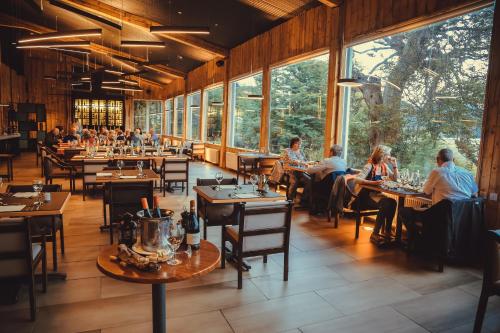 un restaurante con mesas en una habitación con ventanas grandes en Hotel Lago Grey, en Torres del Paine