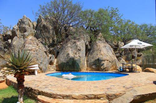 Kamanjab的住宿－考克布什旅館，一座位于大岩石前的游泳池