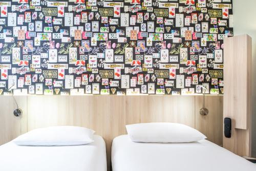 two beds in a room with a wall covered in books at Ibis Styles Reims Centre in Reims