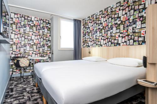 a hotel room with a bed and a wall covered in pictures at Ibis Styles Reims Centre in Reims
