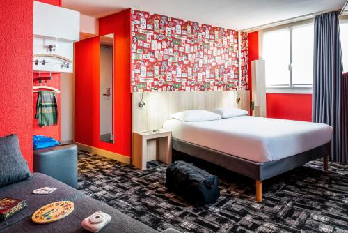 una camera d'albergo con letto e parete rossa di ibis Styles Reims Centre a Reims