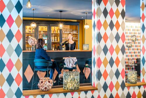 a woman sitting at a bar in a restaurant at Ibis Styles Reims Centre in Reims