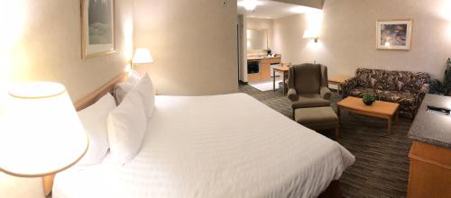 a hotel room with a bed and a living room at Humphry Inn and Suites in Winnipeg