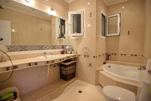 a bathroom with a sink and a tub and a toilet at NEFELI VILLA in Patitiri