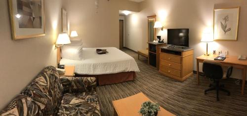 a hotel room with a bed and a desk and a television at Humphry Inn and Suites in Winnipeg