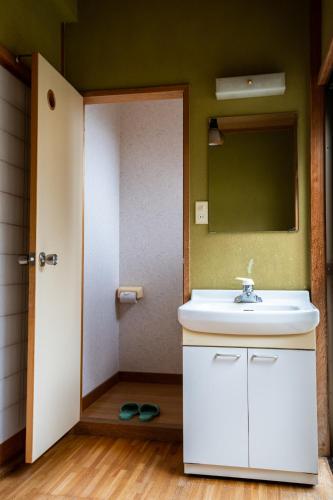 a bathroom with a white sink and a mirror at Toemu Nozawa Lodge in Nozawa Onsen