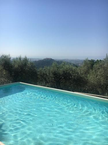 una grande piscina blu con vista sugli alberi di Casa Sarticola a Castelnuovo di Magra
