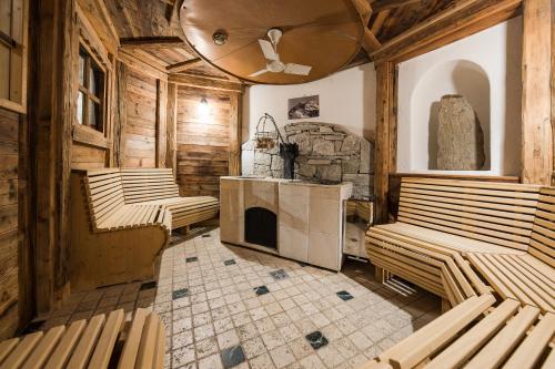 a room with wooden benches and a stone fireplace at Hotel Lärchenhof in Solda