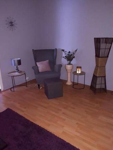 uma sala de estar com uma cadeira e duas mesas em Ferienwohnung zum Schuster em Halbe