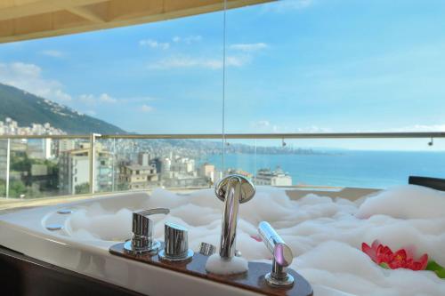 a bath tub in front of a large window at Hollywood Inn Boutique Hotel in Jounieh