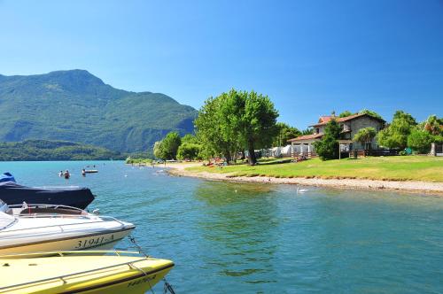 two boats are docked on the water near a beach at Villa Carolina in Domaso
