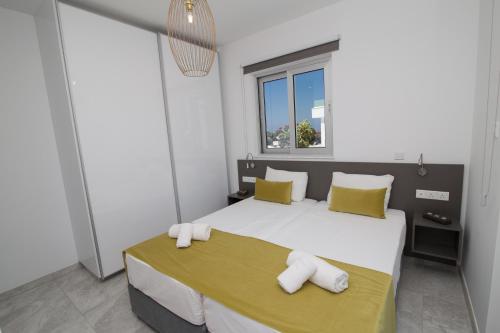 a bedroom with a large white bed with yellow pillows at Fig Tree Bay Residences 1 Lantiana Villa in Protaras