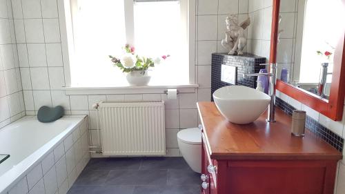 een badkamer met een wastafel, een toilet en een bad bij Huize de Weijde Blick in Wijk aan Zee