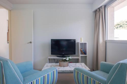 a living room with two blue chairs and a tv at Soho Point Central in Buenos Aires