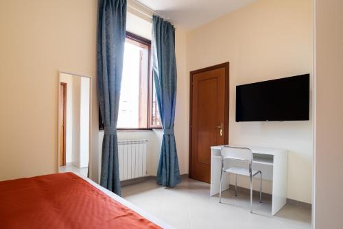 - une chambre avec un lit, un bureau et une télévision dans l'établissement Minerva Monks Inn, à Rome