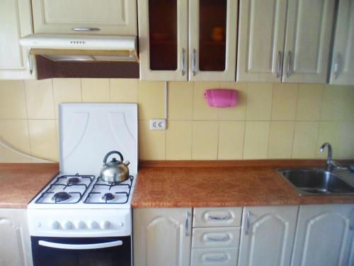 uma cozinha com um fogão e uma chaleira. em Дом em Okhtyrka
