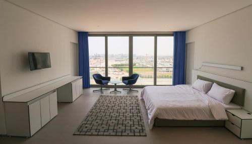 a bedroom with a bed and two chairs and a window at WindWestHome in Dubai