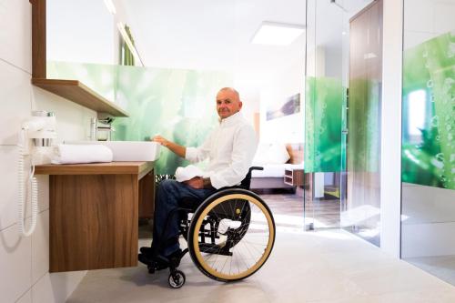 a man sitting in a wheelchair in a bathroom at Hotel Aichingerwirt in Mondsee