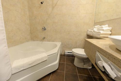 a bathroom with a tub and a toilet and a sink at Hôtel et Pavillons Le Petit Manoir du Casino in La Malbaie