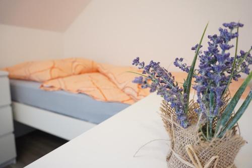 a vase of purple flowers on a table next to a bed at Ferienhaus Lusatia am Töpfer in Kurort Oybin