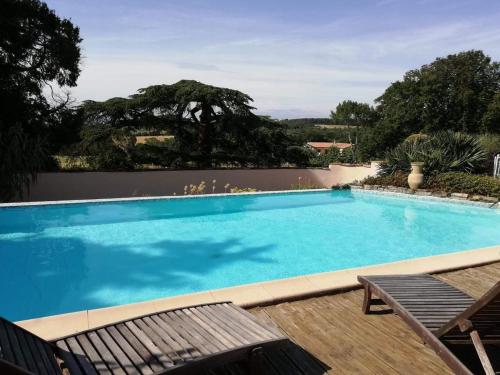 uma grande piscina azul com duas espreguiçadeiras em Château de Villeneuve - Montolieu em Montolieu