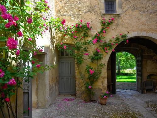 - l'entrée d'un bâtiment en pierre avec des fleurs roses dans l'établissement Château d'Esparron, à Esparron-de-Verdon
