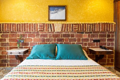 a bed in a room with a brick wall at Hotel Cerro La Nina in Beceña